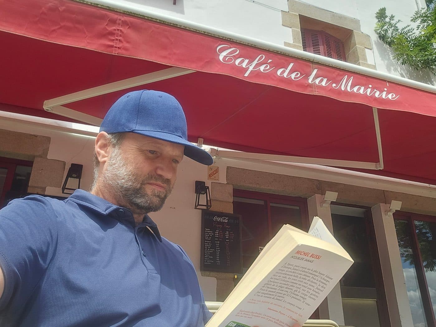 Eric Meade lisant un roman en terrasse au Café de la Mairie, au Croisic